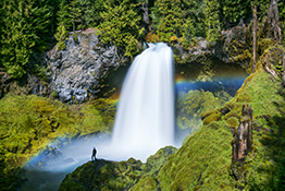 Person Standing in Front of Sahalie Falls with Rainbow, Willamette National Forest, Oregon, USA